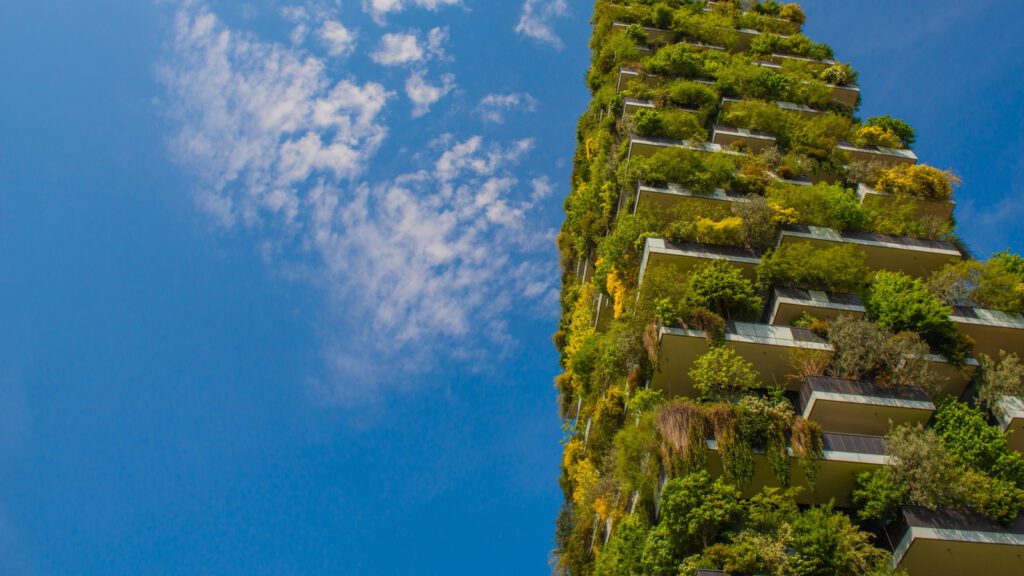 A tower block covered in green plants sits over a blue sky background